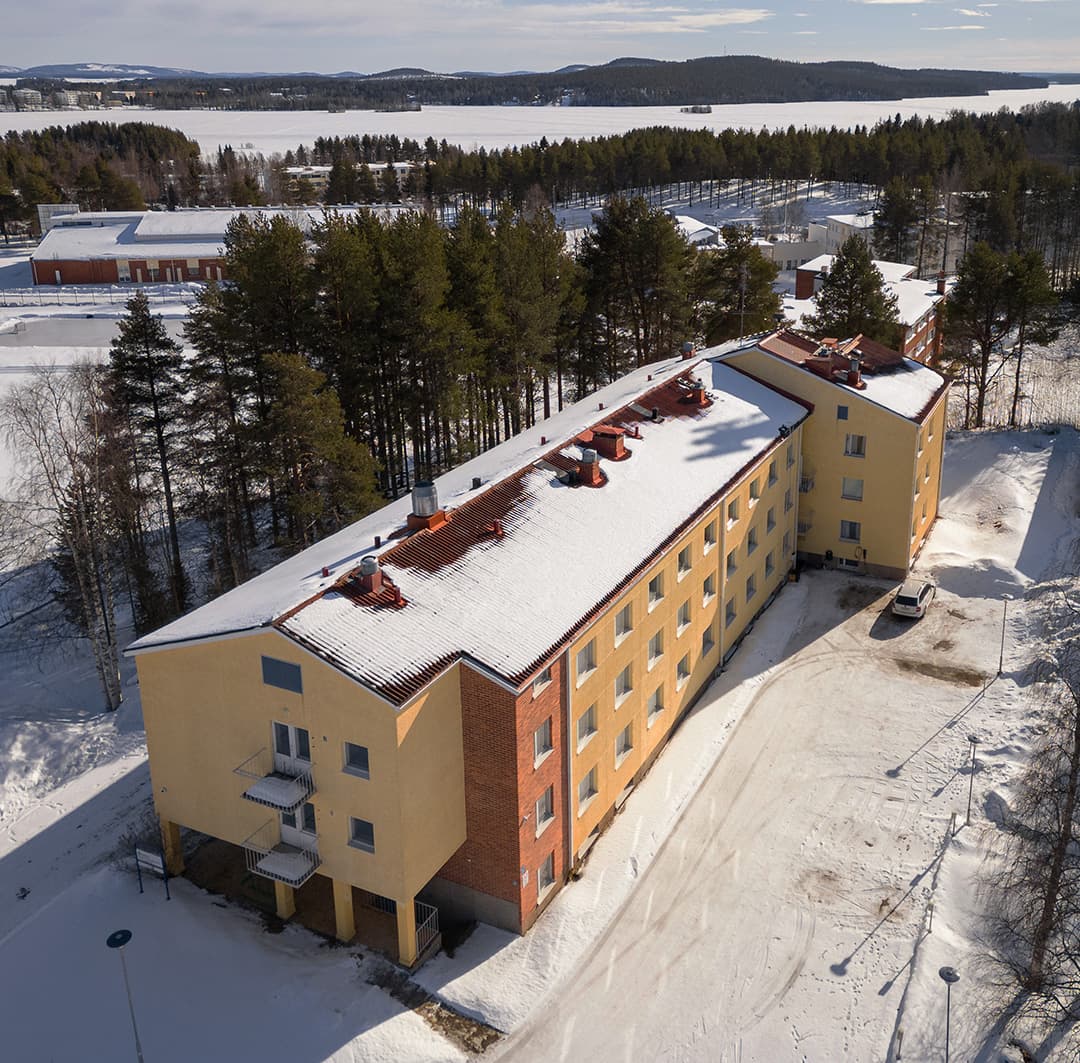 L'Academy Hotel Kemijärvi vu du ciel, le bâtiment entier et son parking sous la neige